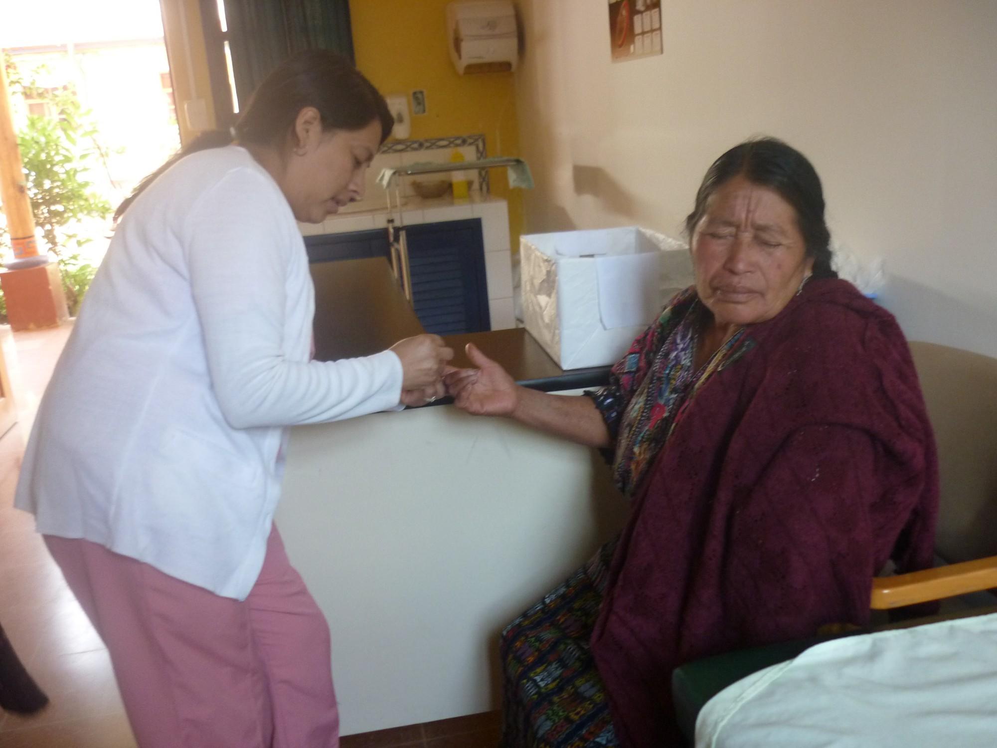 Eine Krankenschwester nimmt einer Maya-Frau in traditioneller Kleidung Blut aus dem Finger ab