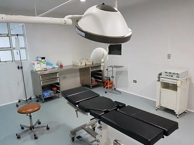 Ein Operationssaal mit Tisch, Lampe und Gerätewagen